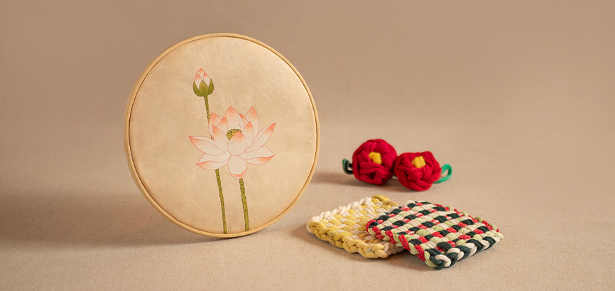 원형 나무 액자 속 연꽃 민화와 동백꽃 모양의 키링, 다양한 색상의 천으로 만든 네모 모양의 티 코스터 2개가 함께 있는 이미지